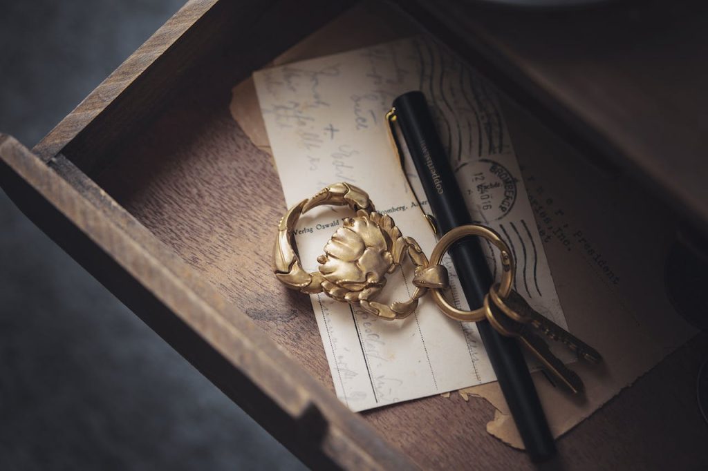 open wooden drawer with vintage keys, gold keychain, black fountain pen, and old handwritten postcards inside