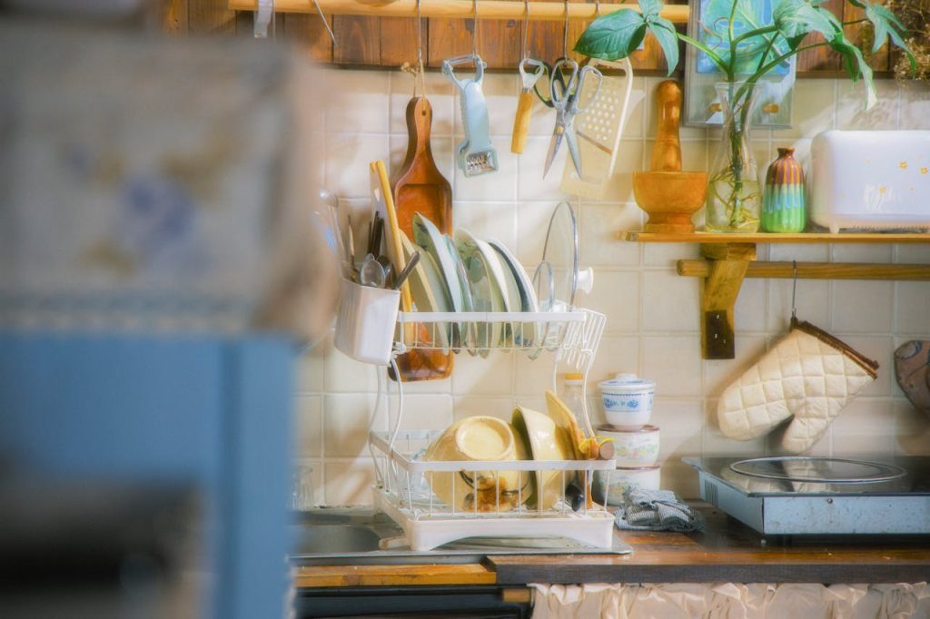 Vintage kitchen with dish rack full of plates, utensils, and bowls, surrounded by retro kitchen tools and decor