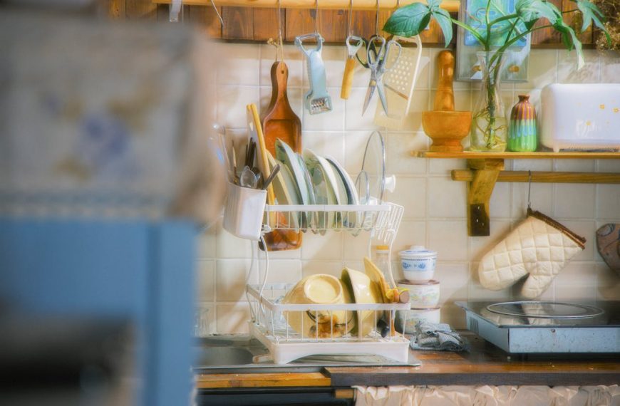 Vintage kitchen with dish rack full of plates, utensils, and bowls, surrounded by retro kitchen tools and decor