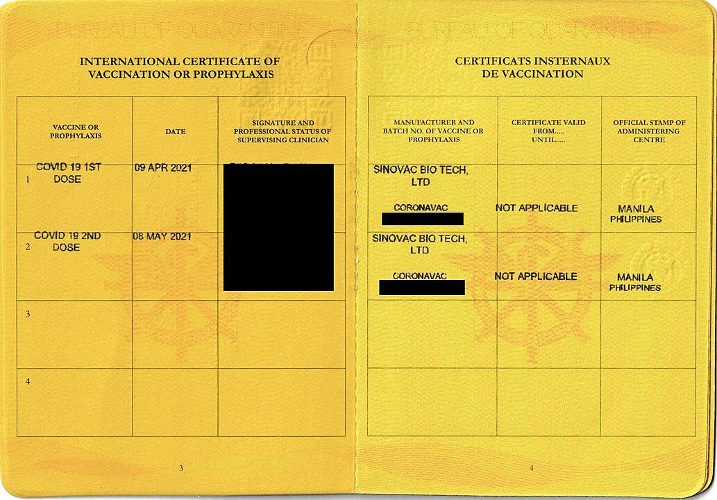 Open yellow vaccination card, personal information section on the left, vaccination records on the right, text entries and stamps, some information redacted with a black box, official document layout, used for medical or travel purposes