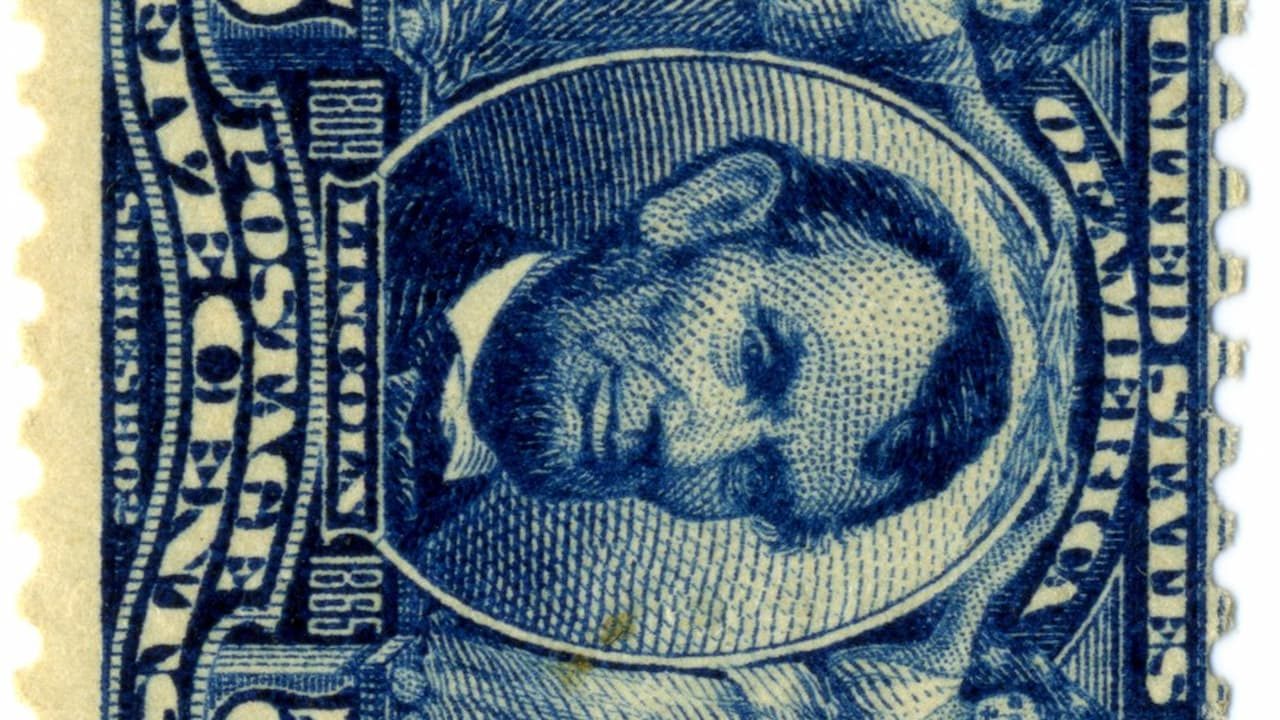 Close-up of a vintage U.S. postage stamp featuring an upside-down portrait of Abraham Lincoln, printed in blue ink, labeled “POSTAGE,” “UNITED STATES OF AMERICA,” and “LINCOLN 1809–1865