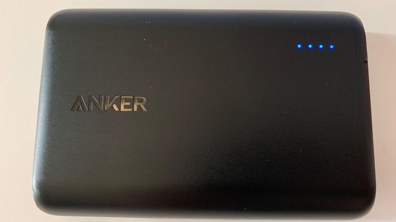 Black Anker portable charger with four blue LED lights indicating full battery charge