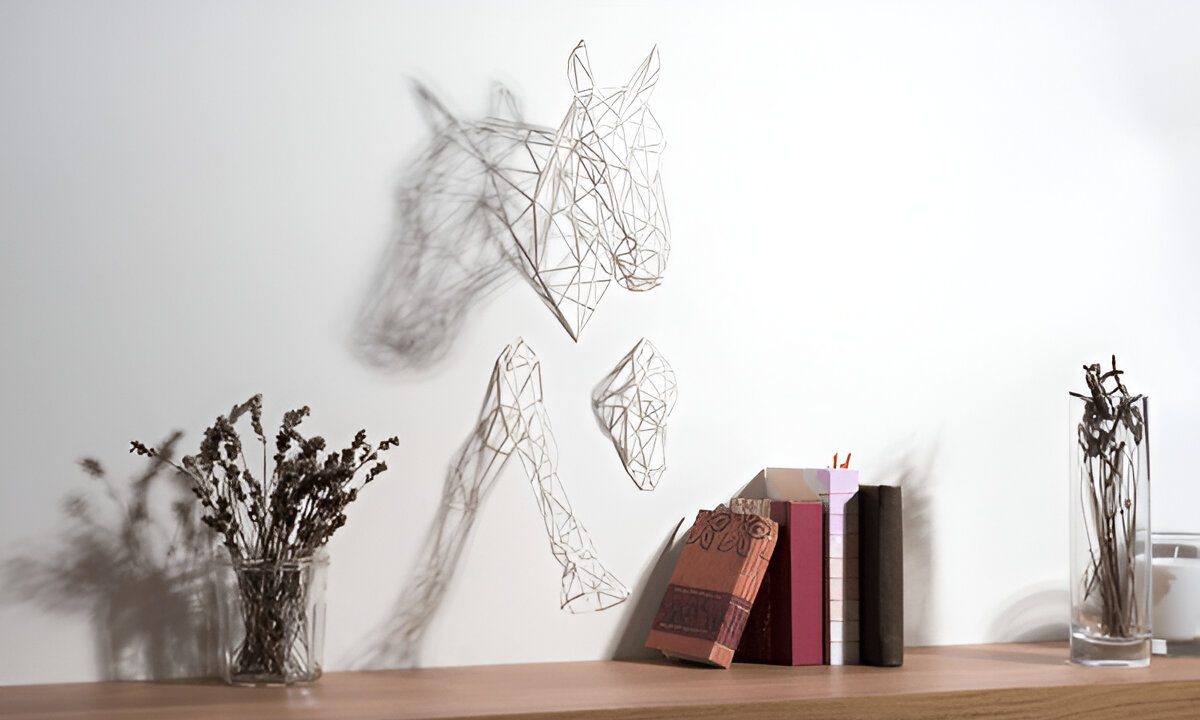 Black horse wire sculpture mounted on white wall and between books and vases on a shelf.