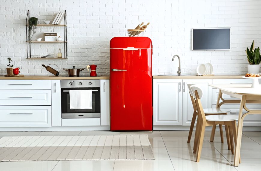 vibrant red retro-style refrigerator, built-in oven, open shelves with decor, small dining table with wooden chairs, minimalistic and bright design