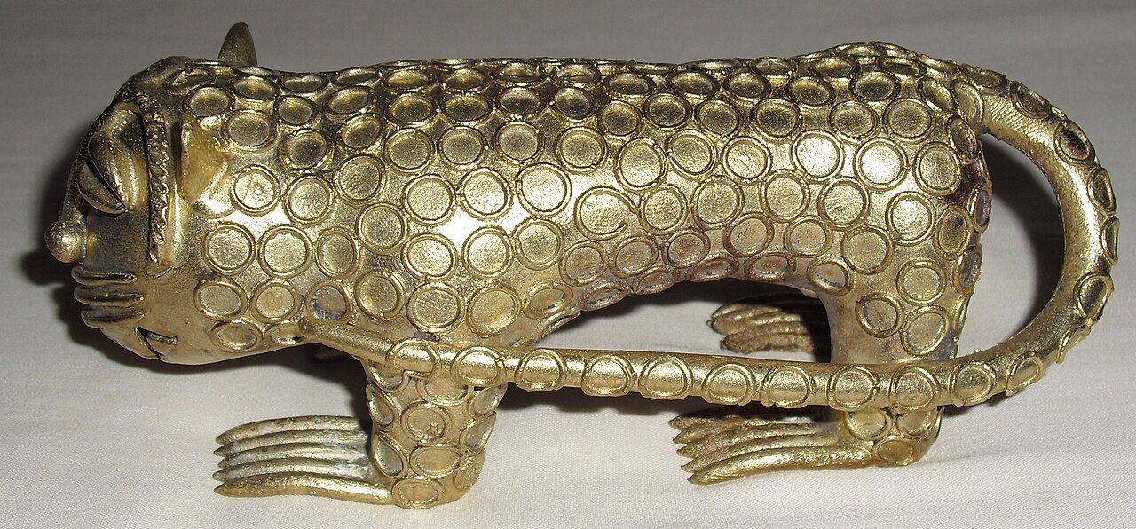 Brass tiger figurine, metallic finish, intricate scale-like texture, curled tail, stylized facial features, sturdy stance, decorative or collectible art piece