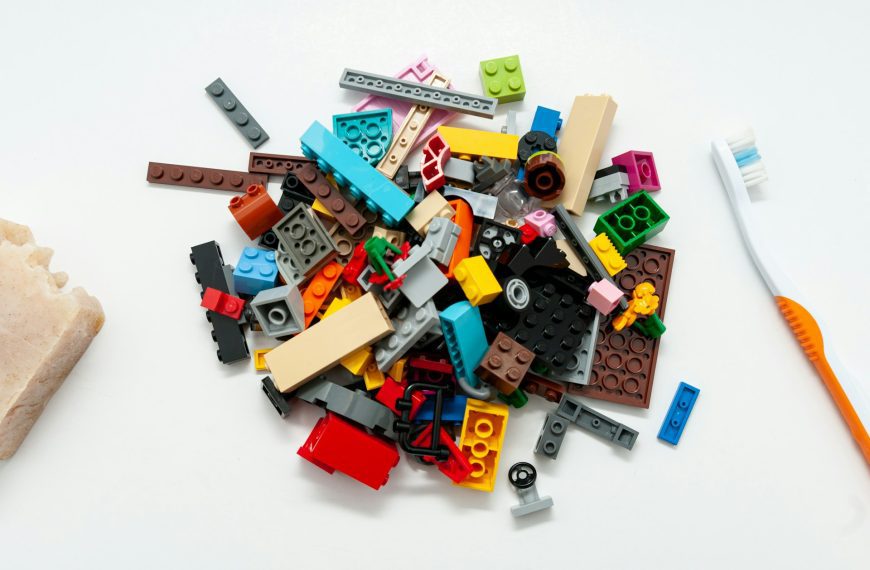 Scattered pile of colorful LEGO building blocks and pieces on white surface, various shapes and sizes