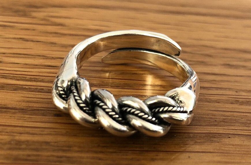 Silver adjustable ring, braided rope design, oxidized detailing for contrast, placed on a wooden surface, rustic and handcrafted appearance