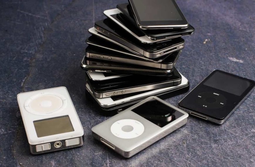 Stack of old iPods and MP3 players in black, silver, and white colors on a dark surface