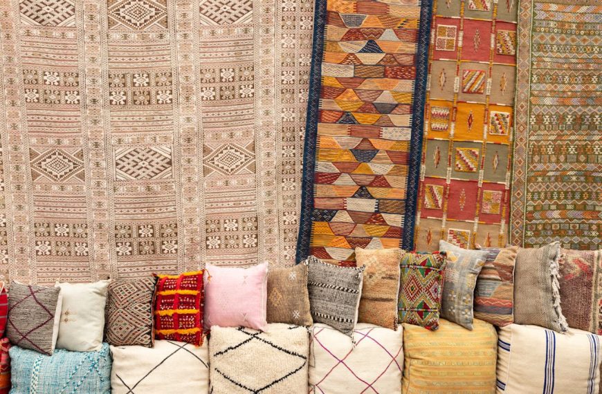 Vibrant Moroccan-inspired display with colorful woven rugs hanging on the wall, assorted textured pillows in earthy tones