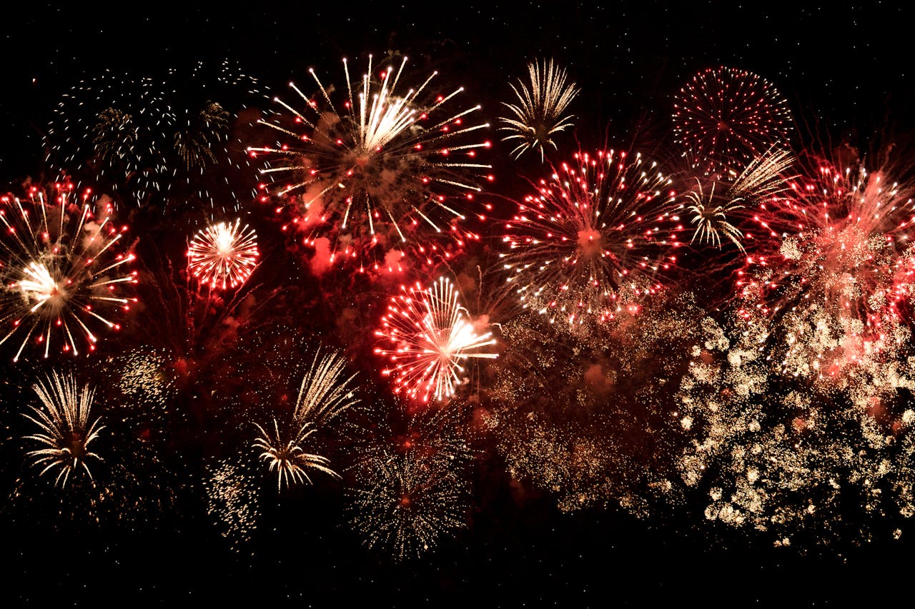 Colorful red and gold fireworks bursting against a dark night sky in various shapes and patterns