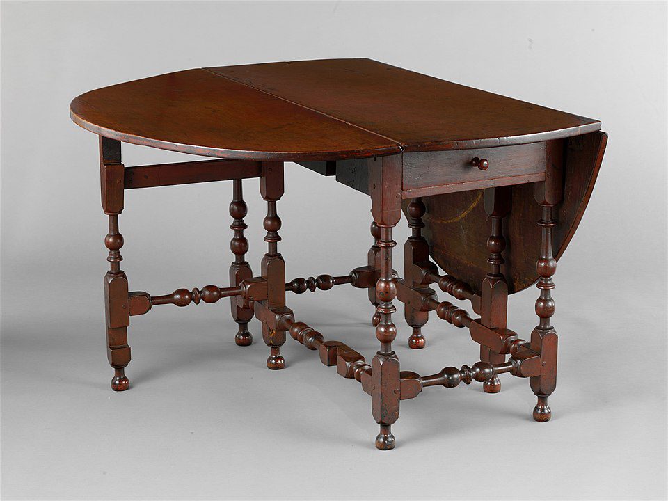 Antique wooden drop-leaf table, turned legs with stretcher supports, central drawer with knob, rich brown finish, classic colonial design