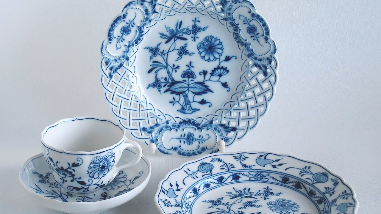 Set of German Meissen porcelain, including a decorative lattice-edged plate, teacup, and saucer, featuring traditional blue floral patterns on white porcelain