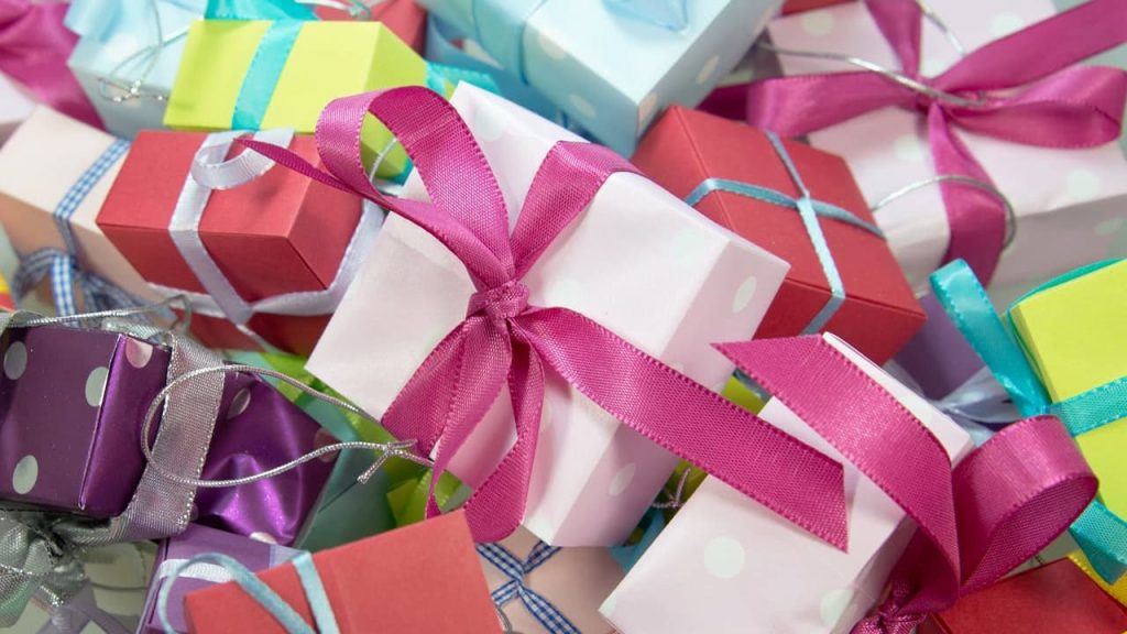 Colorful assortment of small gift boxes, wrapped in pastel and vibrant wrapping paper, tied with satin and metallic ribbons, polka dot patterns, scattered arrangement