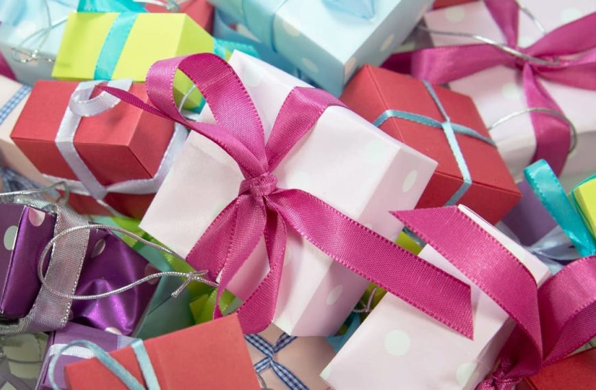 Colorful assortment of small gift boxes, wrapped in pastel and vibrant wrapping paper, tied with satin and metallic ribbons, polka dot patterns, scattered arrangement