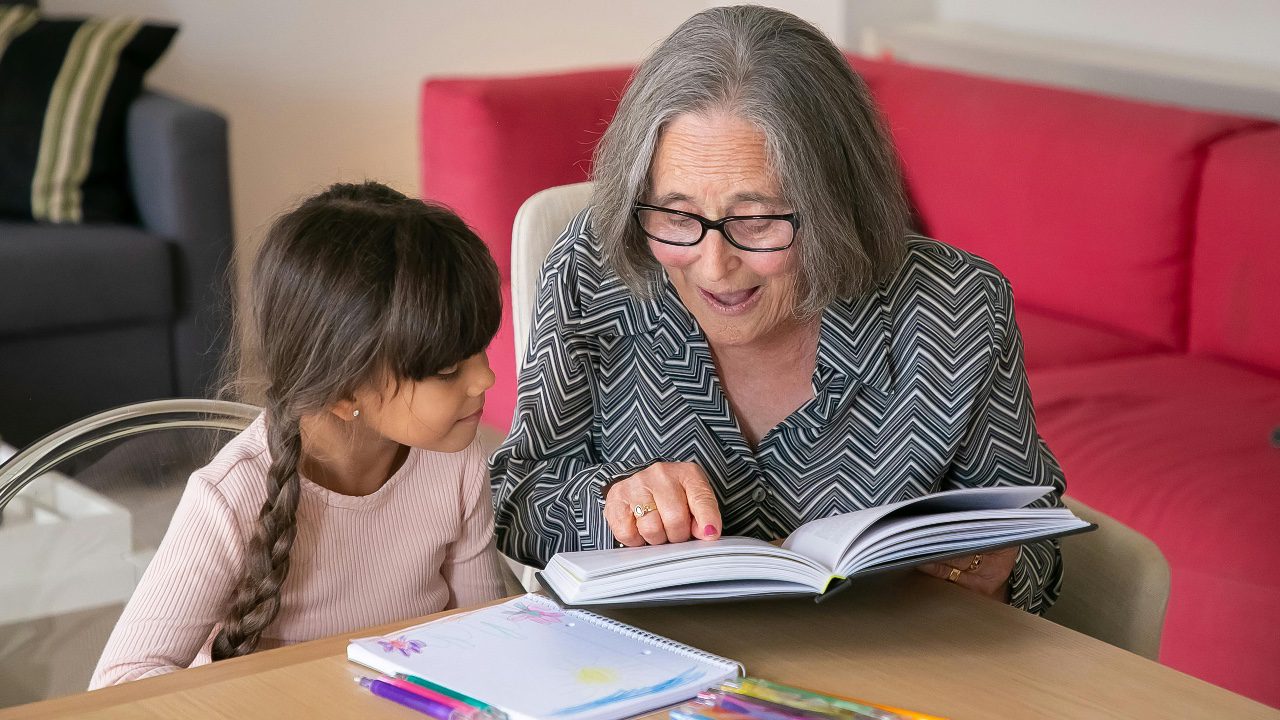 Grandma looking at Book with grandchild 