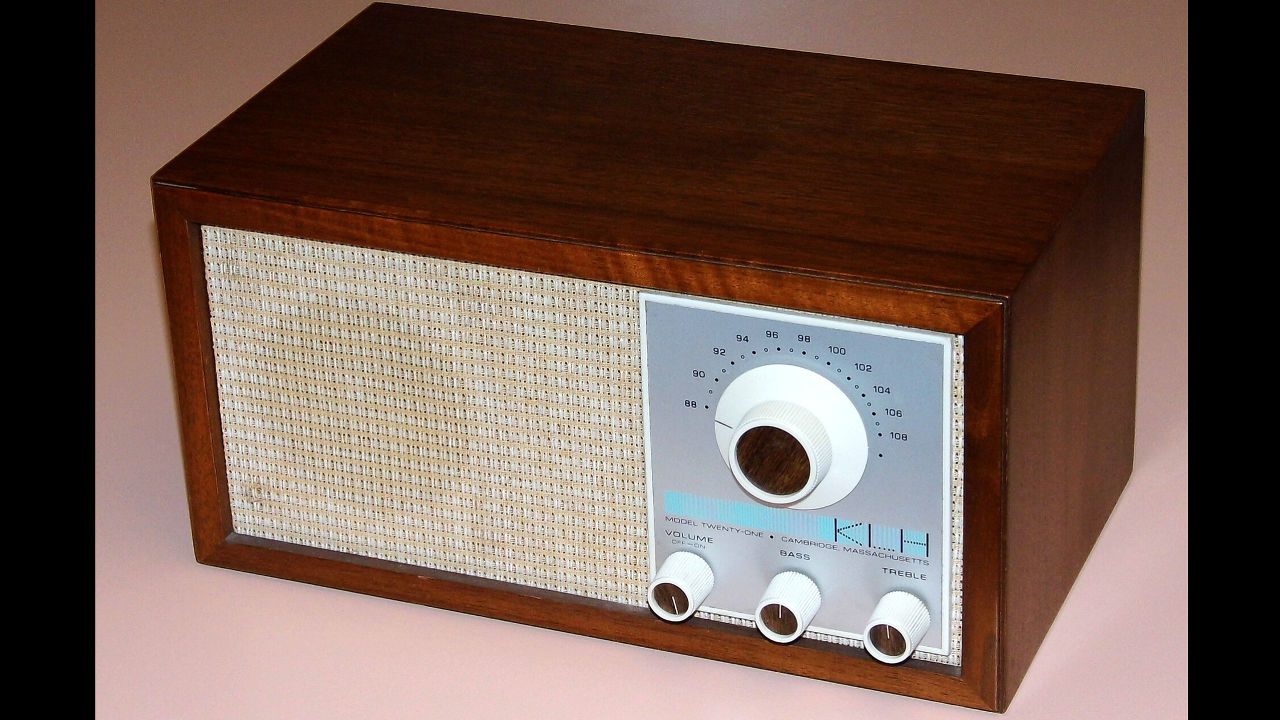 KLH Model Twenty-One FM table radio with wooden casing, woven speaker grill, and three white tuning knobs on a silver panel