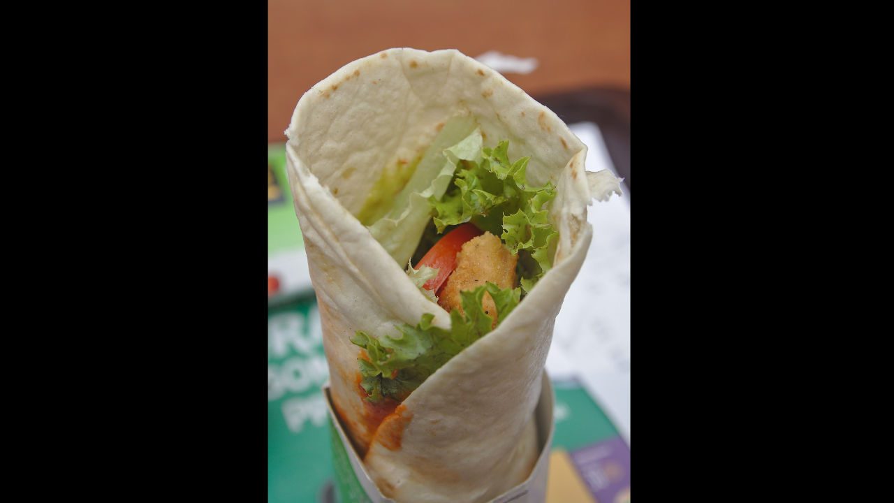 Close-up of a McDonald’s Snack Wrap with grilled tortilla, lettuce, tomato, and crispy chicken on a paper tray