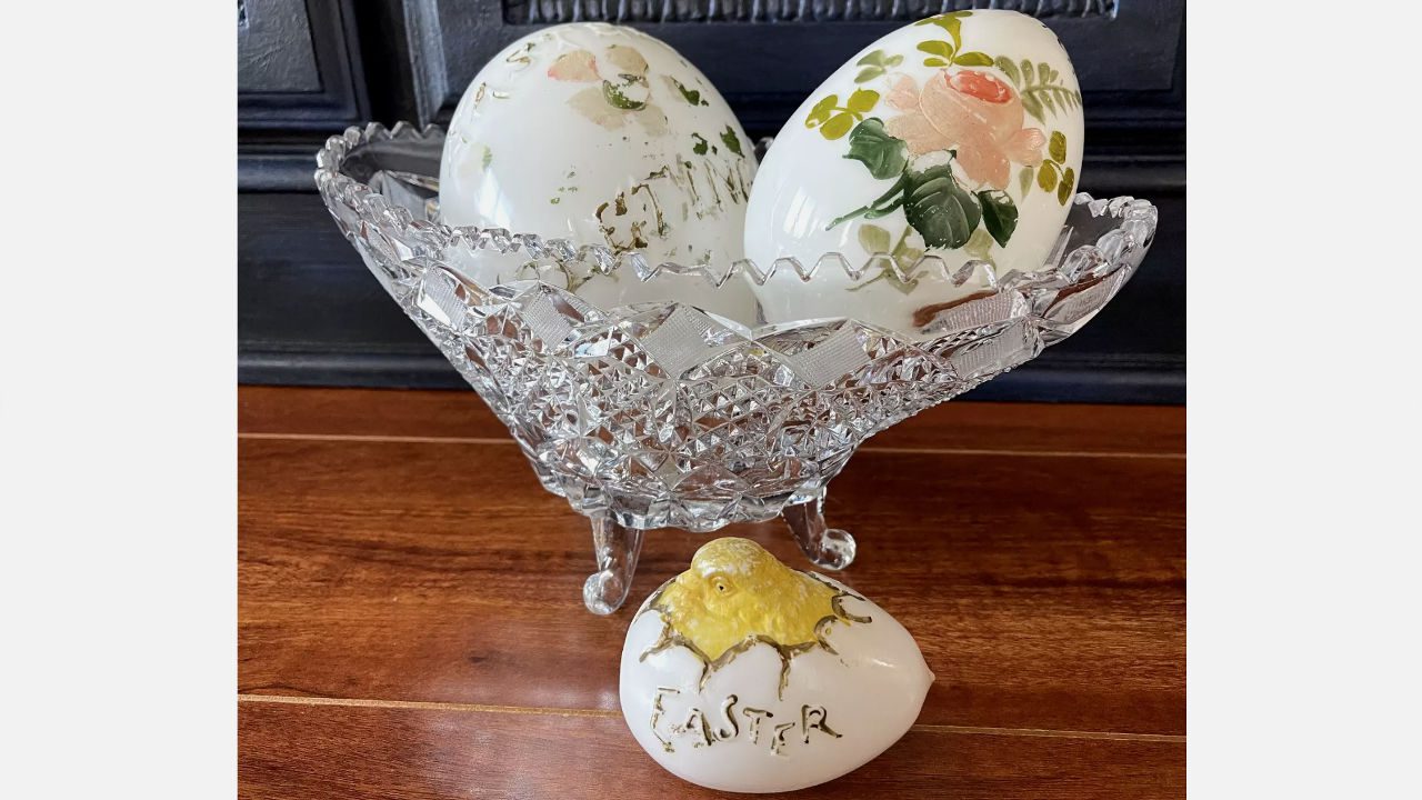Decorative milk glass Easter eggs with floral designs in a cut crystal bowl, small chick-themed egg labeled “Easter” in front