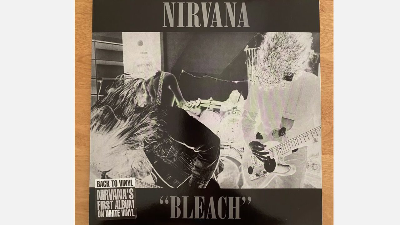 Nirvana "Bleach" vinyl album cover, black and white high-contrast negative image of the band performing, bold silver band name at the top