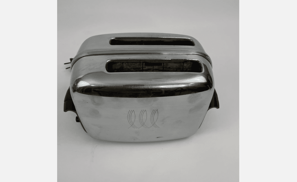Vintage metal toaster, chrome finish, dual slot design, black plastic side handles, power cord visible on the left, placed on a plain white surface.