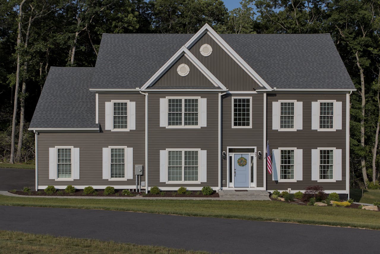 Two-story house with dark siding and white trim, featuring contrasting shutters and a light blue front door