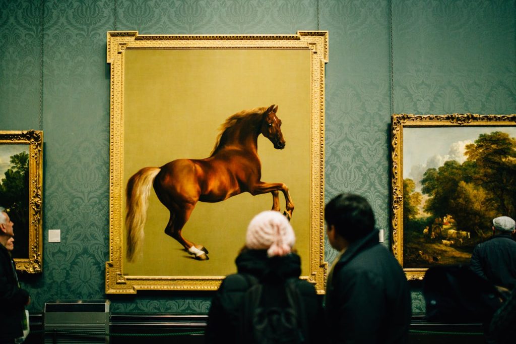 Two people viewing a large painting of a leaping brown horse in a gold frame, displayed on a green wall in an art gallery, surrounded by other framed artworks