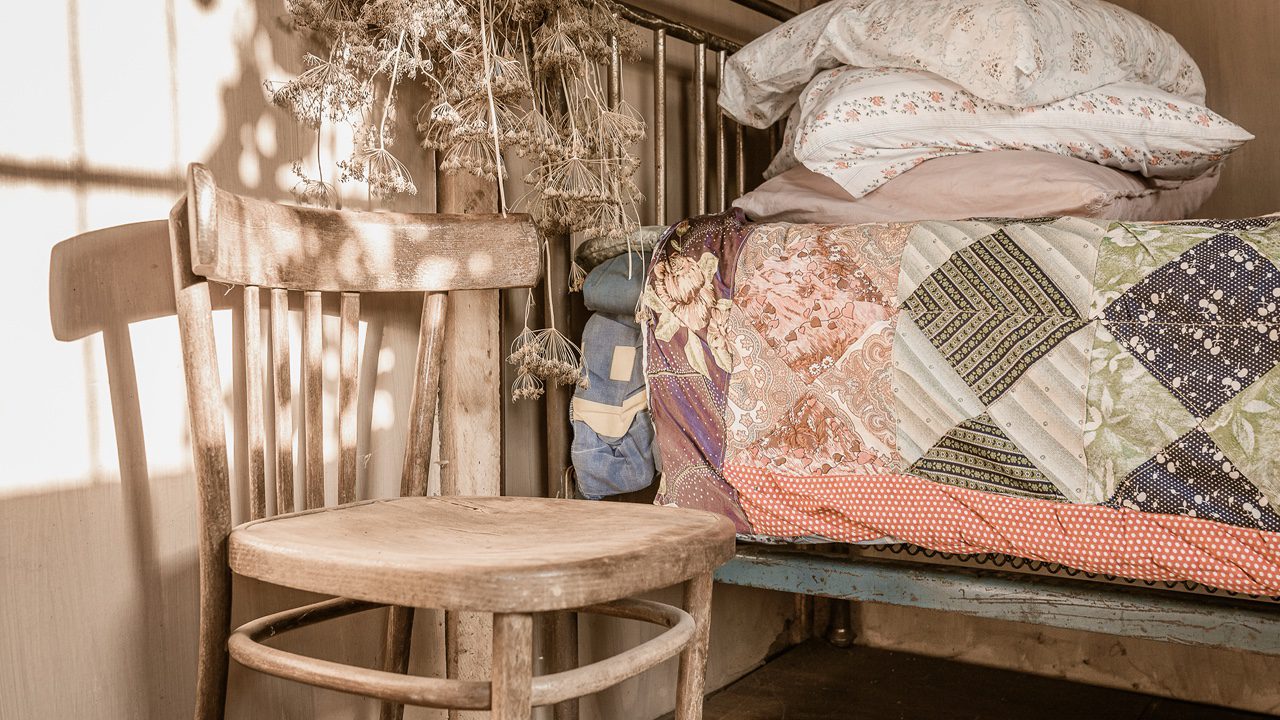 Rustic decor depicting a chair and a bed covered with a rustic quilt