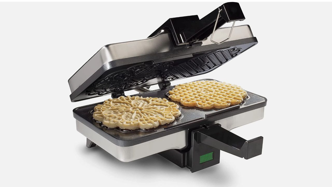 Electric pizzelle iron with its lid open, cooking two round pizzelle cookies on patterned heating plates