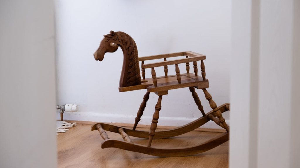 wooden rocking horse, vintage design, placed on wooden floor, white walls in background