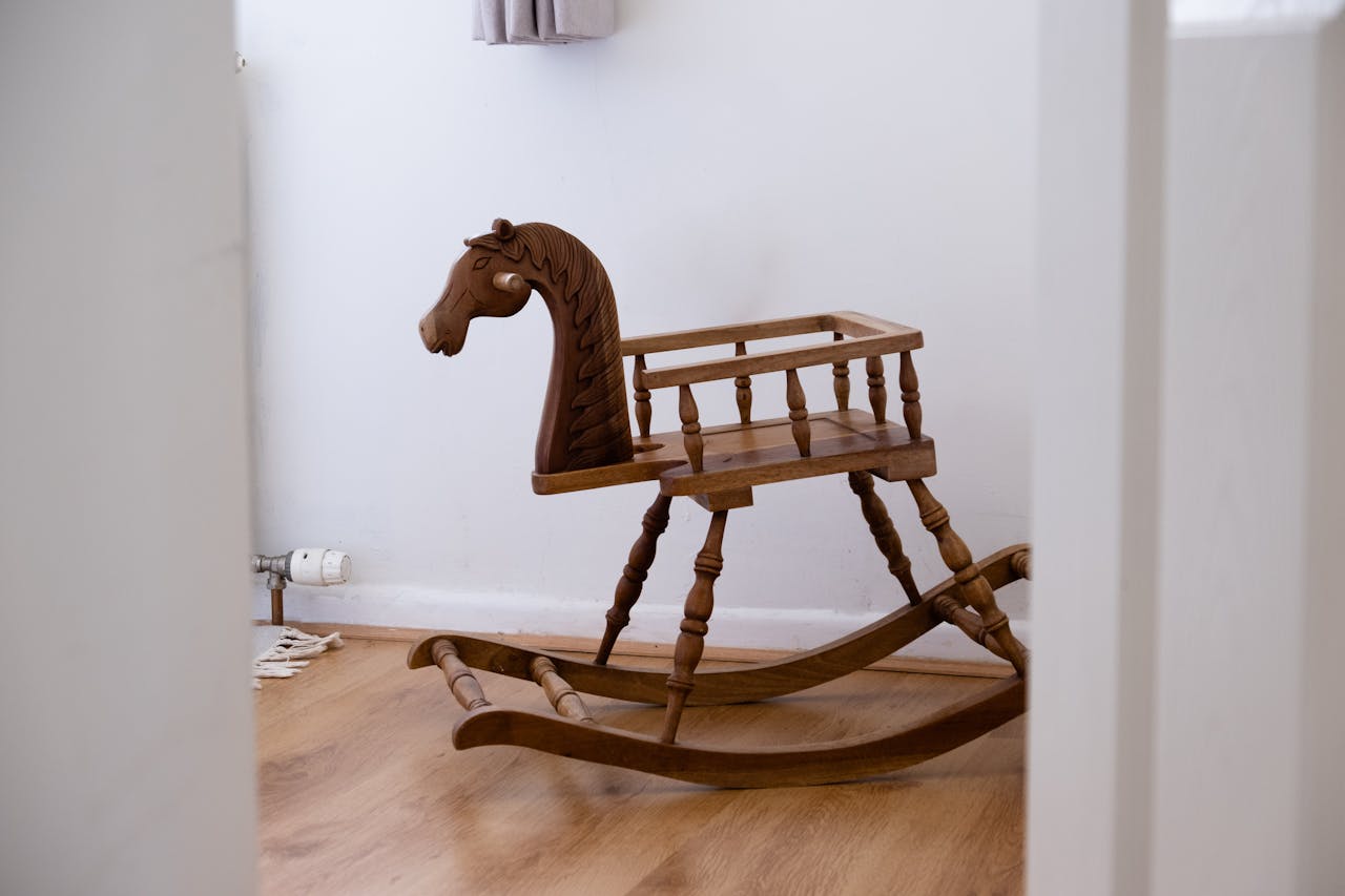 wooden rocking horse, vintage design, placed on wooden floor, white walls in background