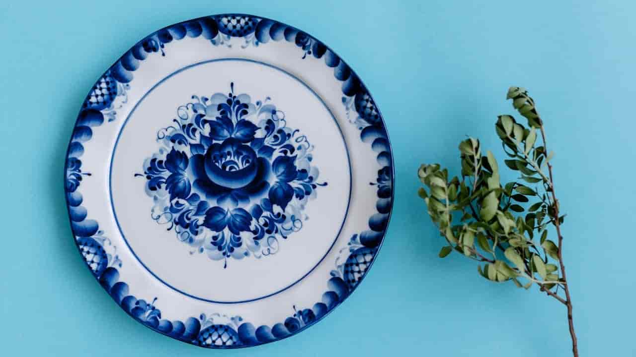 Set of vintage porcelain plates with blue floral patterns, displayed upright on a white lace tablecloth