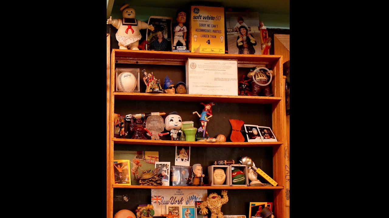 Shelf filled with a variety of tchotchkes, including toys, figurines, baseball memorabilia, and framed photos