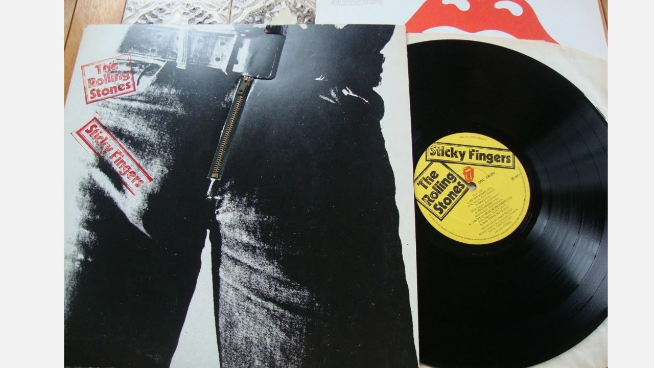 The Rolling Stones "Sticky Fingers" vinyl album cover with iconic black and white close-up of jeans, functional zipper detail