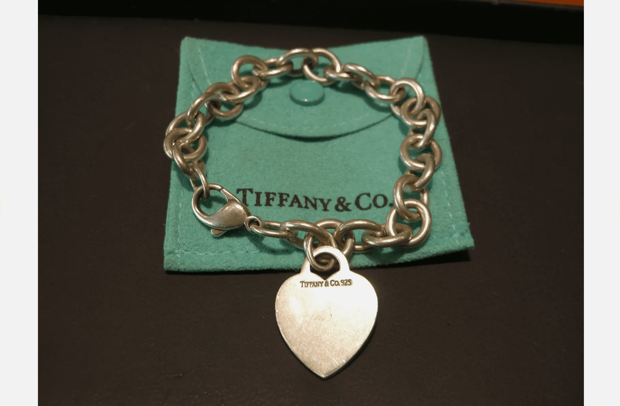 Tiffany & Co. silver chain bracelet with heart-shaped pendant, displayed on a signature turquoise pouch with snap button