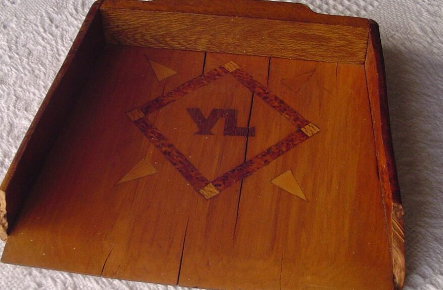 wooden tray, rectangular shape, raised edges, decorative design in the center with diamond pattern, letters "VL" inscribed, warm brown finish, placed on a textured white surface