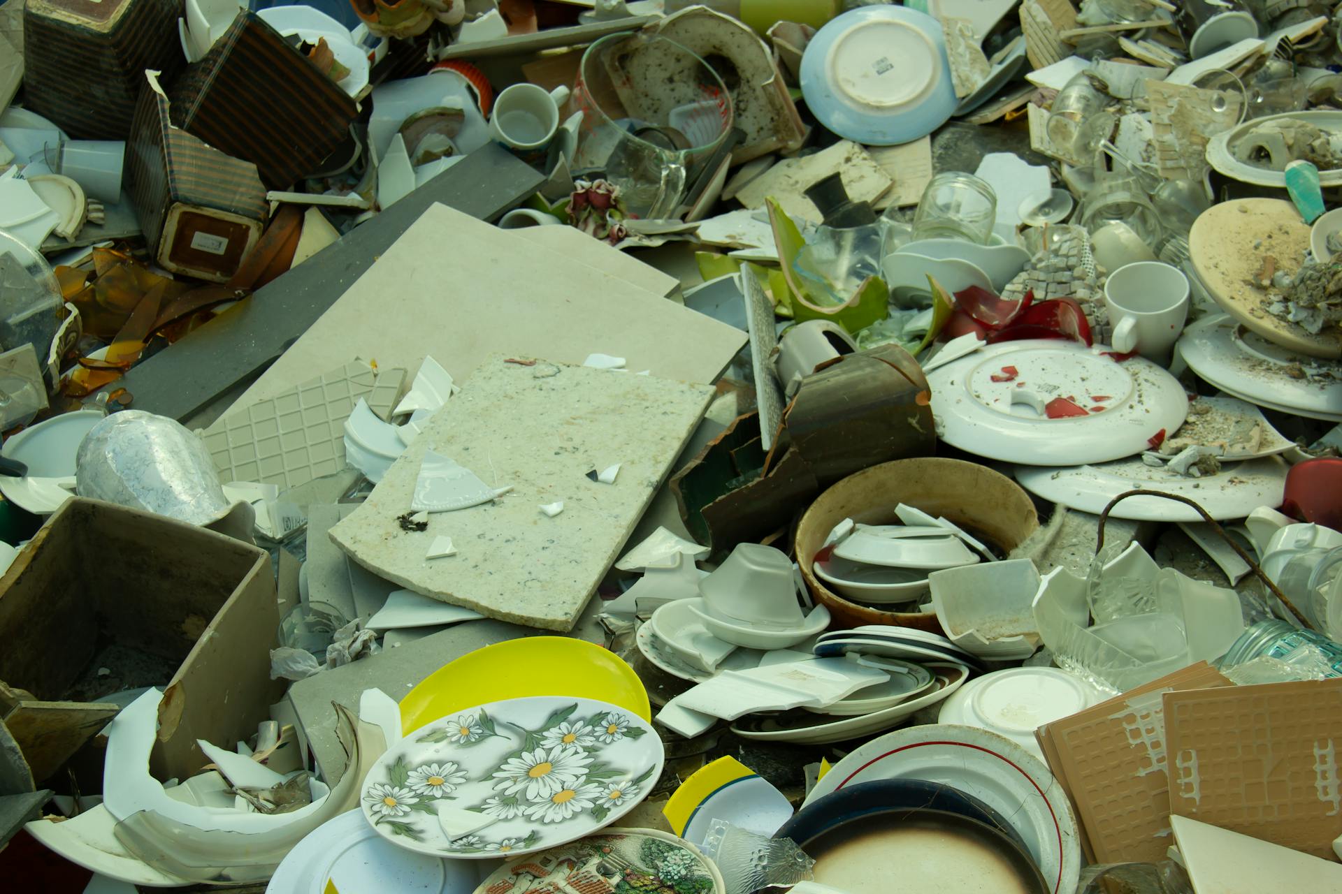 Broken ceramics, shattered pieces, jagged edges, glazed surface, various colors, cracks and chips, scattered fragments, pottery texture