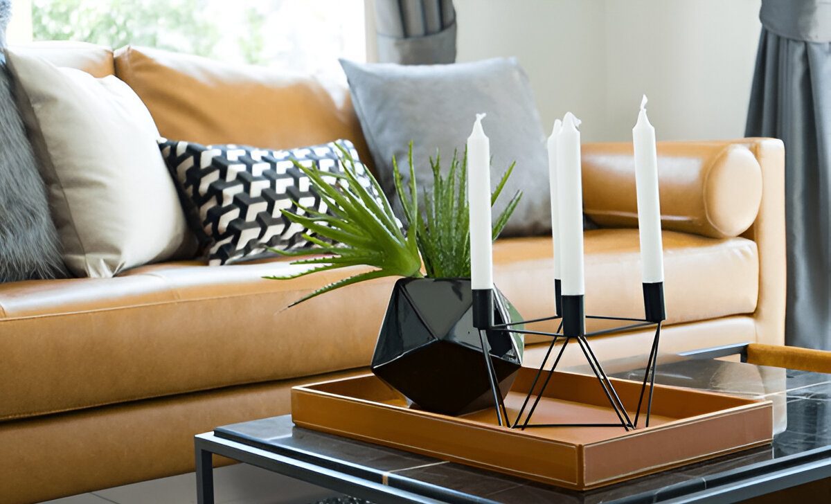 Brown leather sofa near a coffee table with black vase and modern candle holder