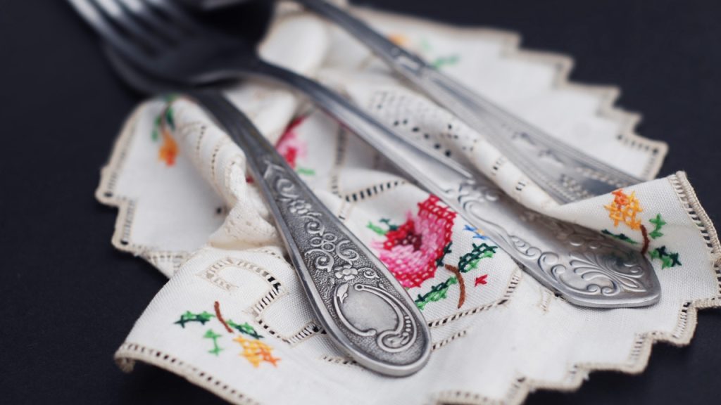 Napkins embroidered with floral designs under silverware