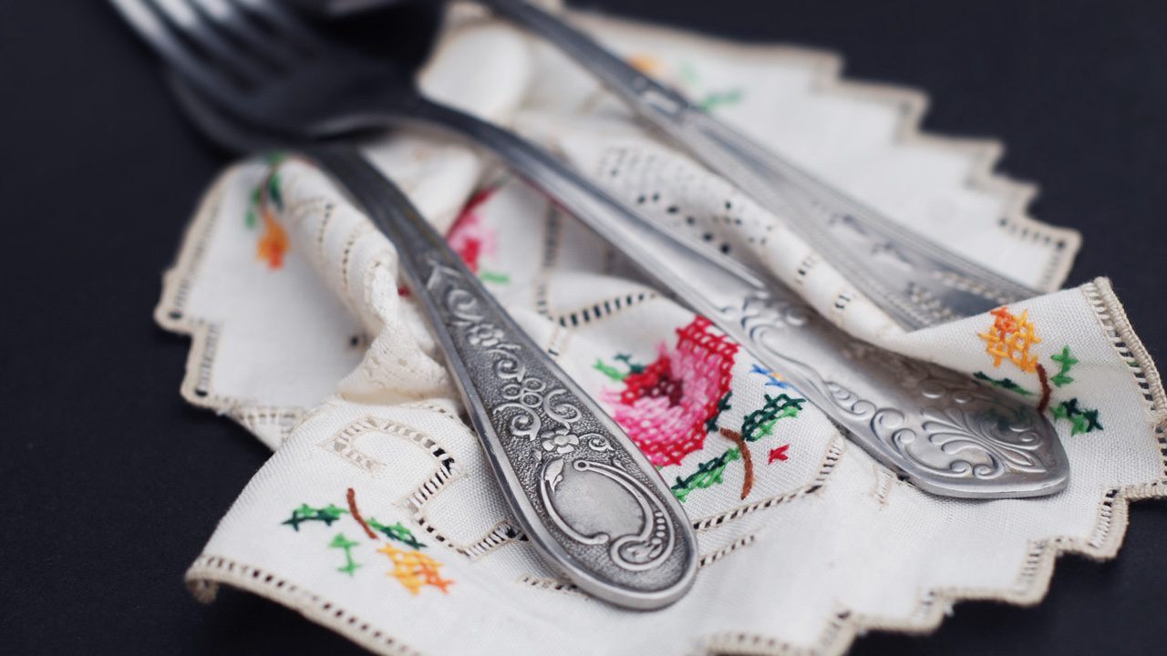 Napkins embroidered with floral designs under silverware 