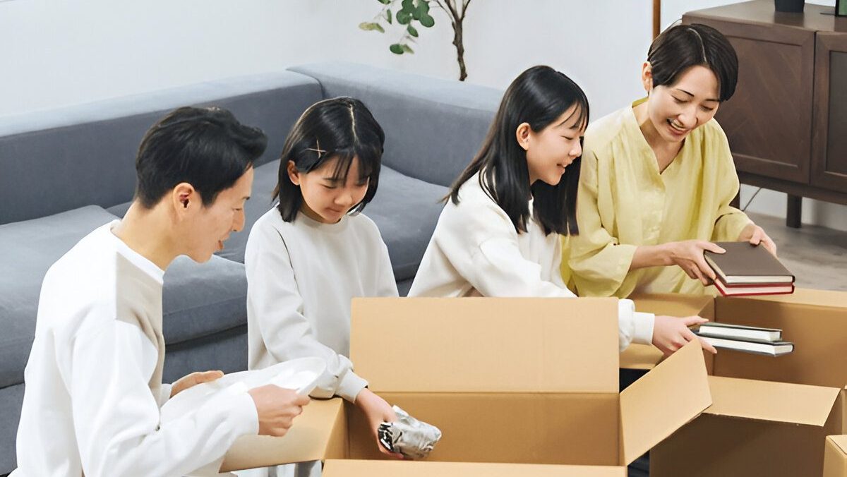 A smiling family of four sitting in a living room, unpacking items from cardboard boxes together