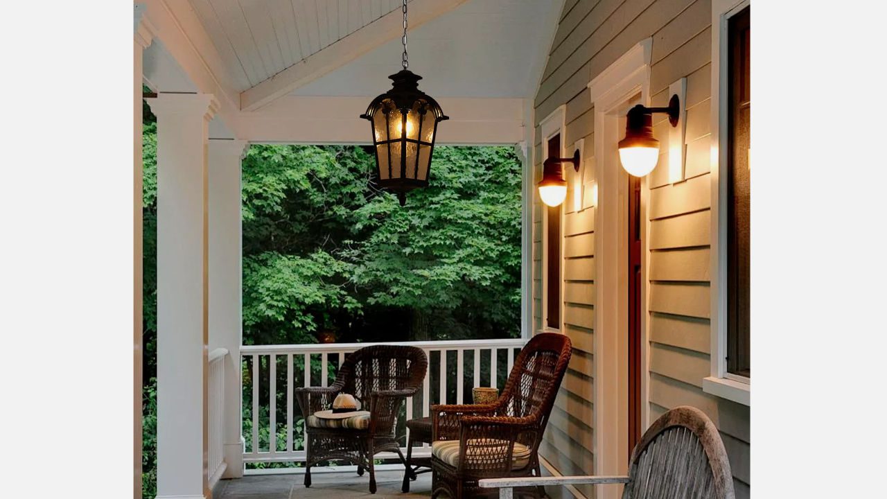 Front porch with hanging lantern-style light fixture and wall-mounted globe sconces, wicker chairs, and wooded background