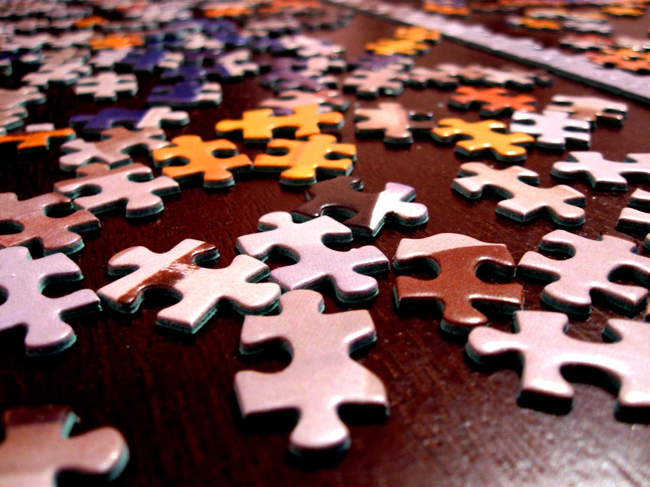 Scattered colorful jigsaw puzzle pieces on a dark wooden surface