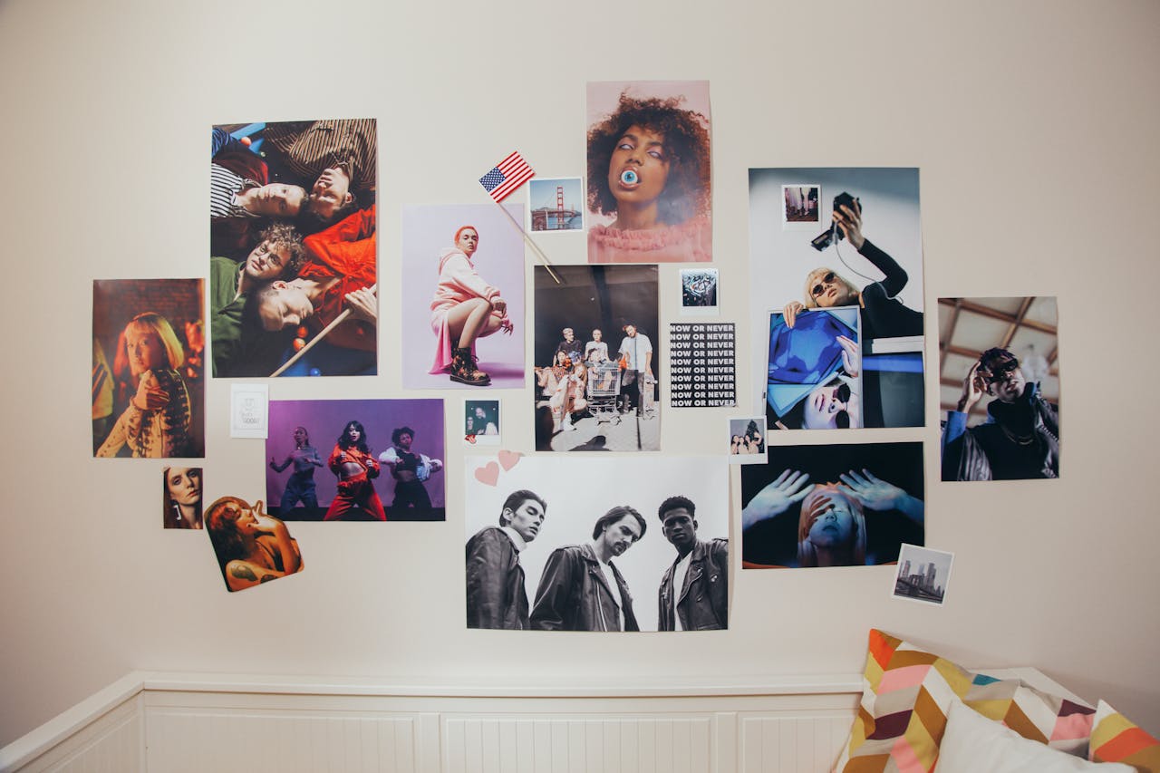 Wall collage of colorful fashion and lifestyle portraits, including diverse people posing, dancing, and taking selfies, arranged above a white headboard with a geometric pillow