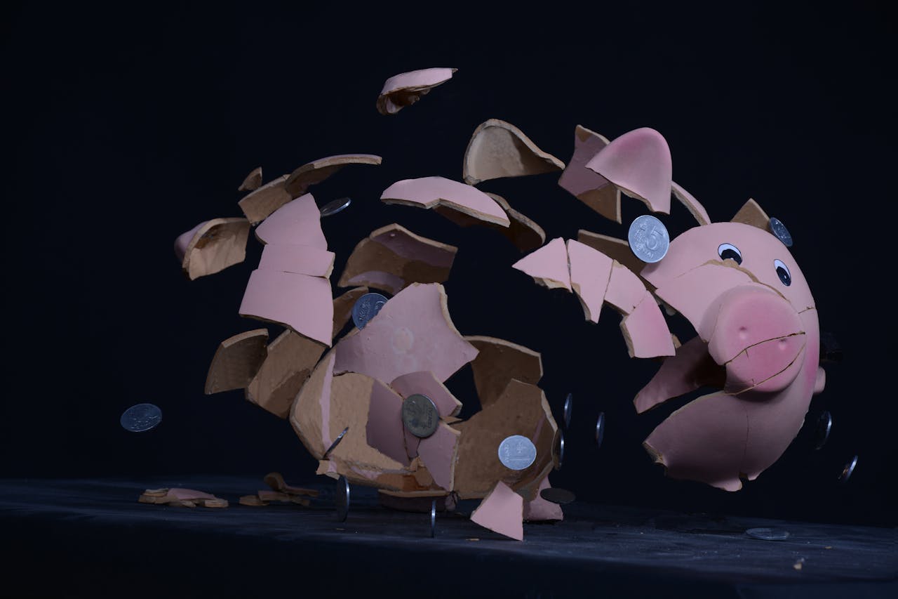 Shattered pink piggy bank, flying ceramic pieces, scattered silver coins, dark background, moment of impact frozen, symbolizes broken savings or financial loss