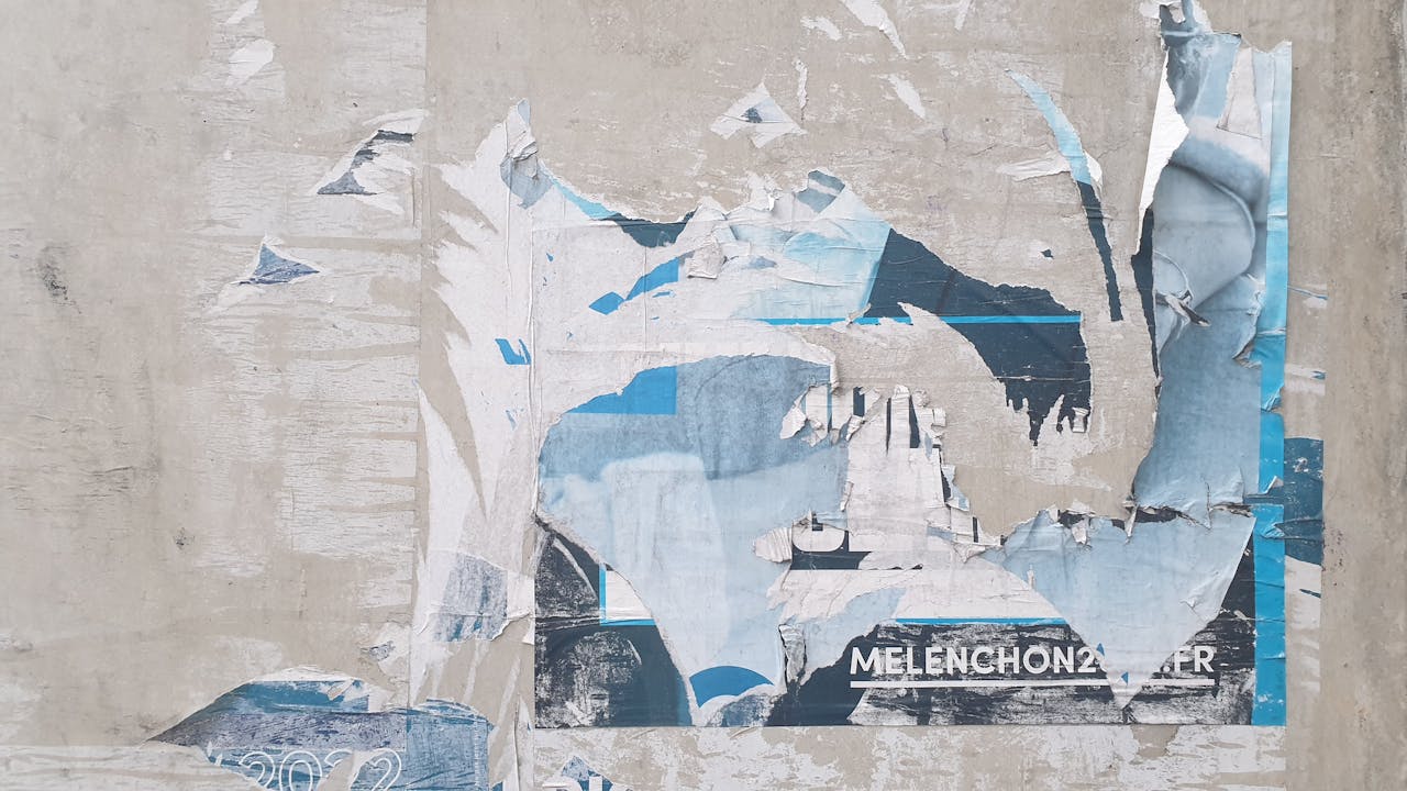 Worn and weathered wall, peeling paint and torn paper layers, exposed patches of blue, white, and beige, textured surface with abstract patterns