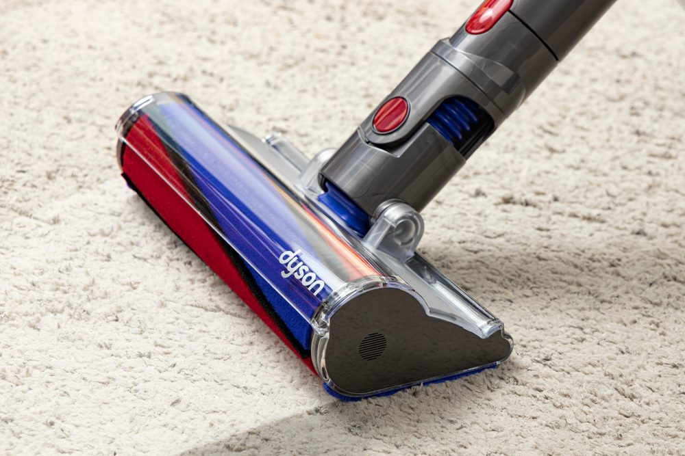 Dyson cordless vacuum cleaner on a carpet, angled view of the roller brush head