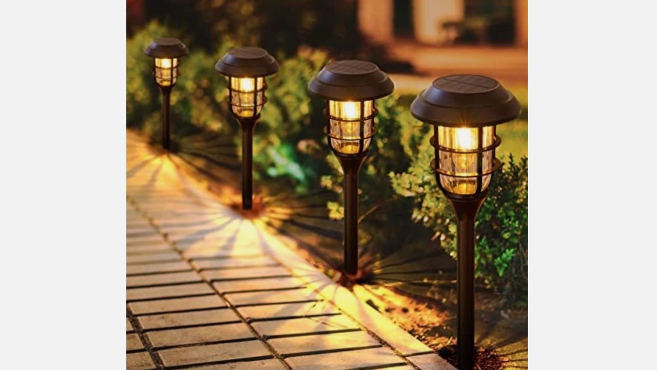 Solar-powered pathway lights illuminating a garden walkway at night, casting patterned shadows on the ground