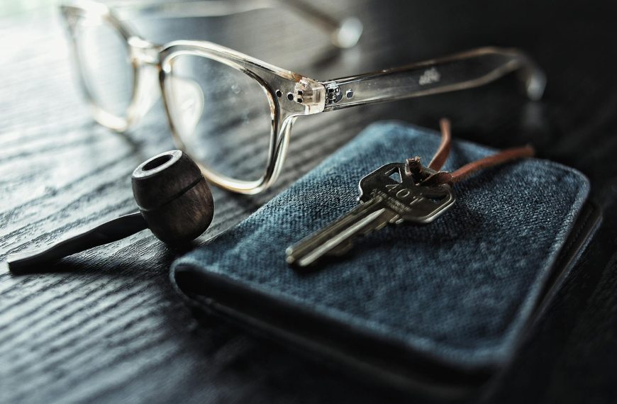 Selective Focus Photo of Silver Key Beside Brown Smoking Pipe and Clear Eyeglasses