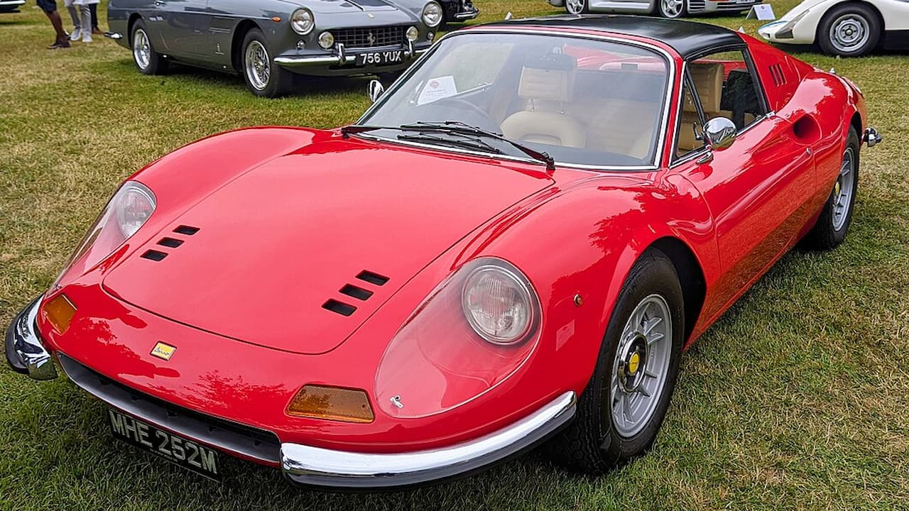 1973 Ferrari Dino 246 GTS, red exterior, sleek curvy design, targa top roof, round headlights, chrome bumpers, mid-engine layout, classic Ferrari badging, parked on a smooth roadway