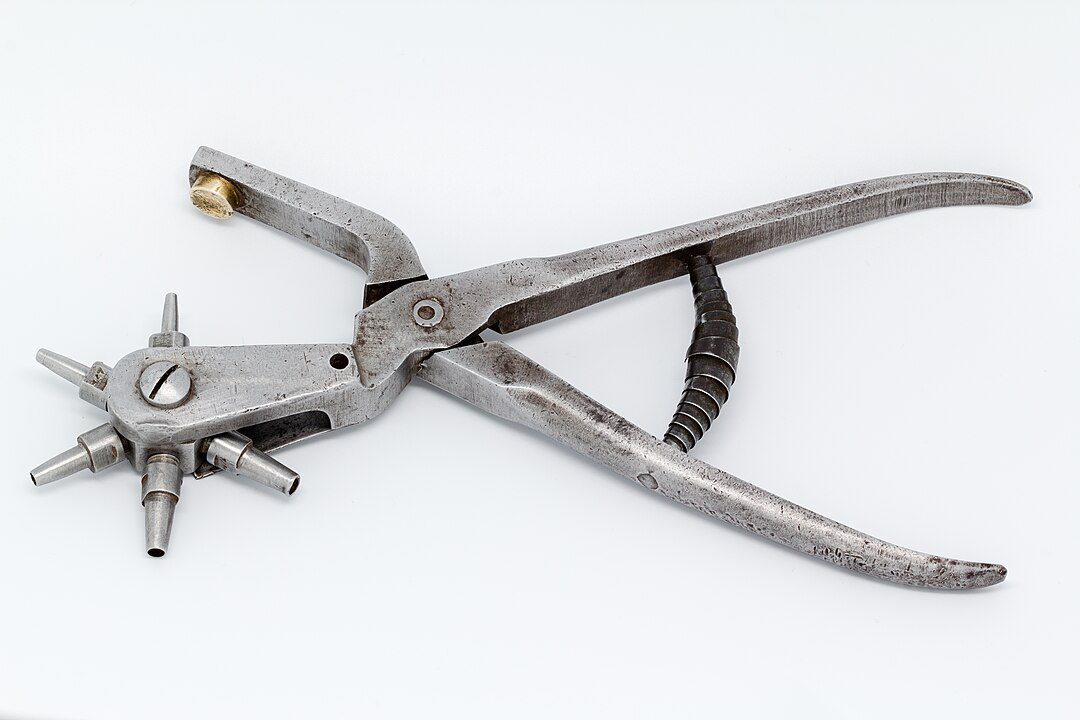Metal rotary leather hole punch tool, with adjustable wheel and handles, placed on a white background